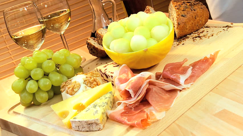 Healthy selection of cheese, oils, fruit & parma ham served with white wine as a modern lifestyle lunch
