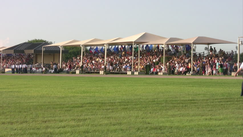 Video of USAF enlisted Basic Training graduates marching onto parade field for ceremony. Blue uniform with Drill Sergeants barking commands. Family and spectators. Lackland AFB San Antonio, Texas. 