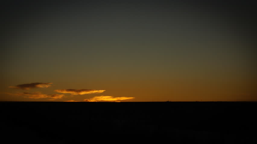 The night sky turns to day as a thin layer of clouds turns bright orange. HD 1080p time lapse video.