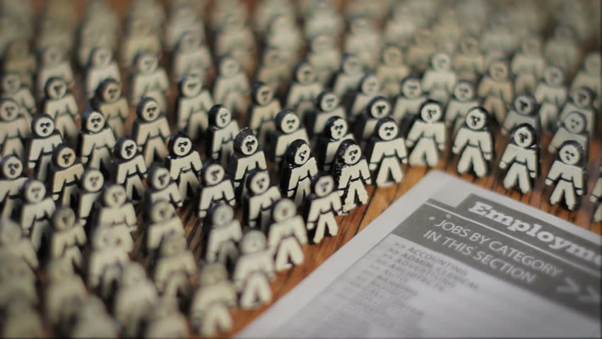 A crowd of anonymous men surround the employment page of the newspaper, dolly shot