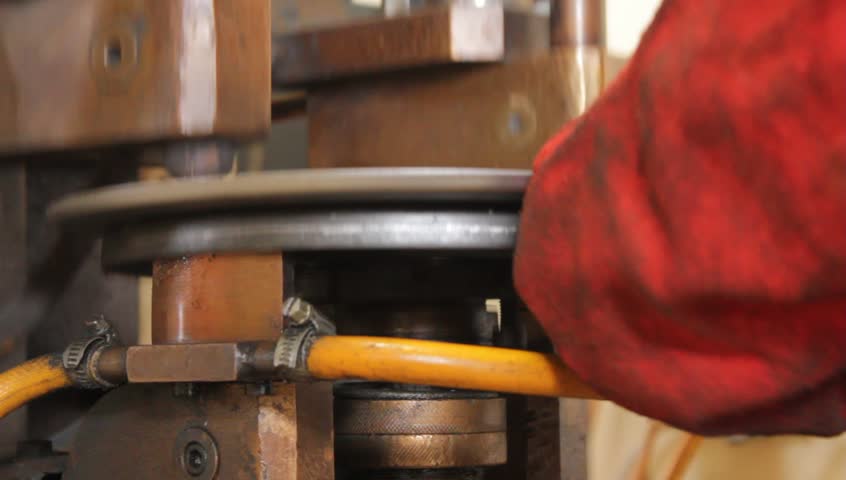 A worker operates a Welding Machine to Make Parts for a Brake Assembly at a factory that manufactures and assembles Auto Parts