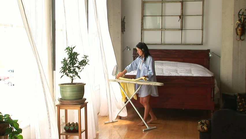 Young woman ironing in bedroom