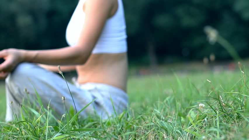 Woman sitting on the grass in park and meditating, dolly shot - 1080p