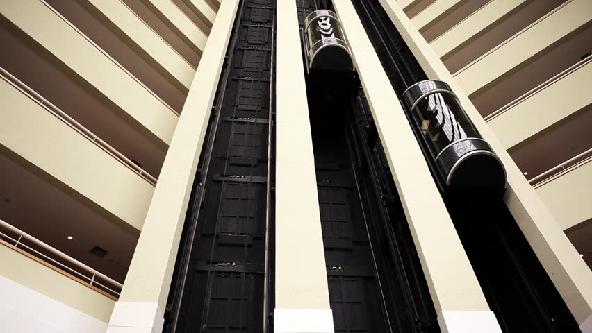 Elevators in lobby of luxury hotel moving up and down in modern architecture surrounding 