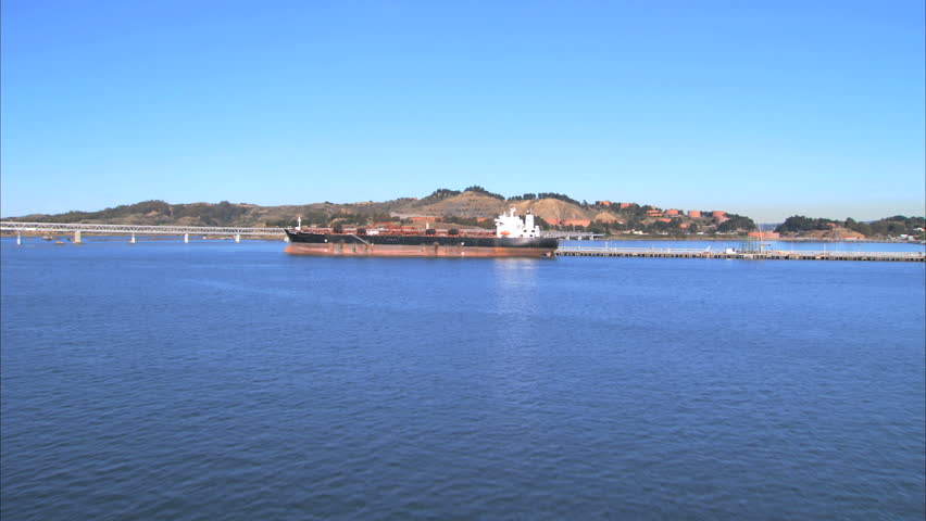 Aerial view of docked  oil tanker with Oakland Bay Bridge behind