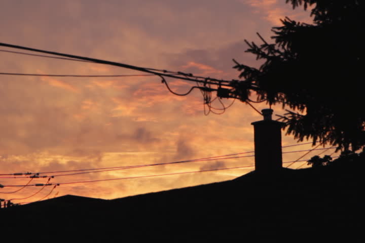 Suburban sunset. Timelapse. Colorful timelapse clouds move over suburban rooftops and wires.  