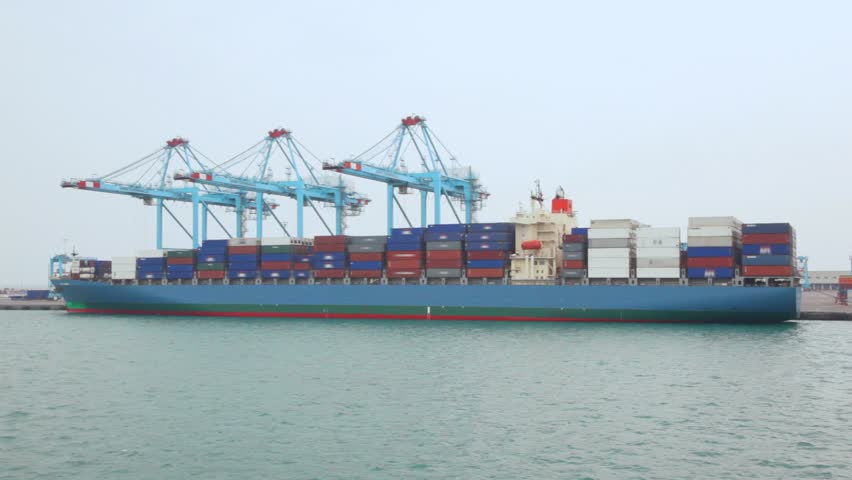 camera moving past by barge with containers in seaport