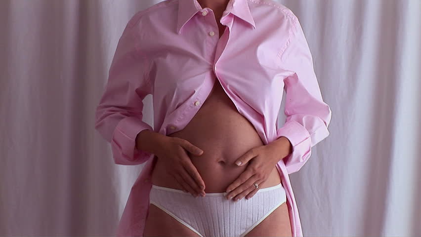 Pregnant woman posing in man's pink shirt