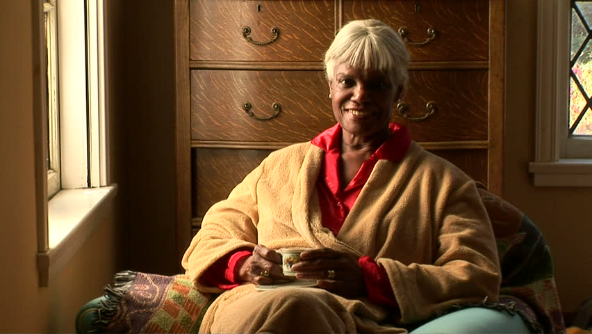 Senior woman drinking tea by bedroom window