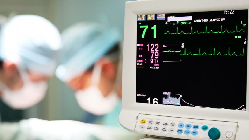 Patient cardiogram monitoring in operation room with surgeon on background