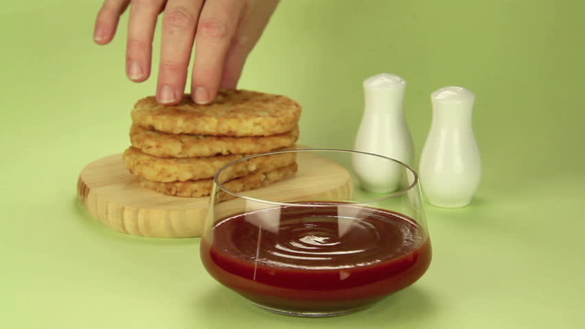 Hash brown dipped in ketchup with salt and pepper ready to serve.