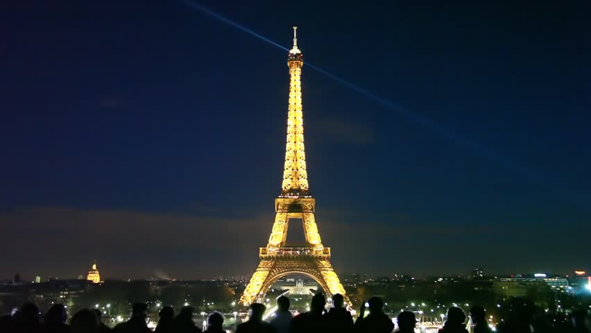 PARIS, FRANCE - JANUARY 2: People look at night Eiffel Tower with rotating search lights on January 2 2010 in Paris, France. The Eiffel Tower is the worldÃ¢â¬â¢s most visited paid monument.