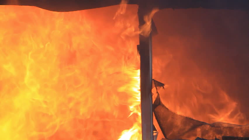 House burning with intense flames in slow motion through window. Total loss and destruction.