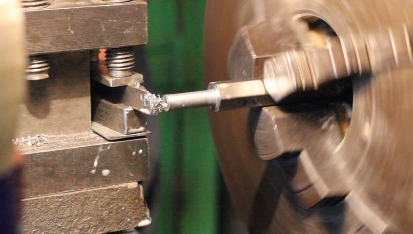 Industrial worker makes a stud using a lathe machine 