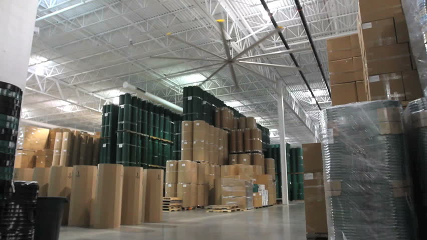 A pan across a large warehouse ends on a smiling worker 