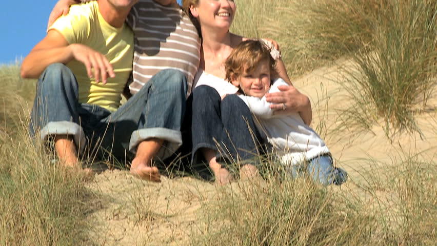 Attractive young caucasian family enjoying outdoor time together on coastal sand dunes  filmed at 60FPS