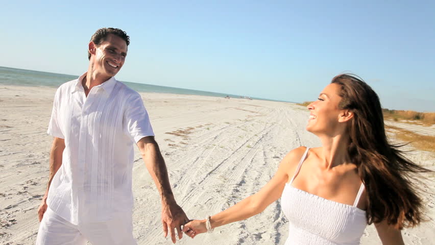 Attractive healthy couple having fun being together walking on the beach