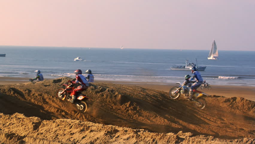 Dirt bike event on a beach with boats as spectators
