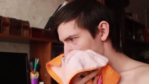 young guy has a runny nose, wipes his nose with a handkerchief, sneezes into his handkerchief