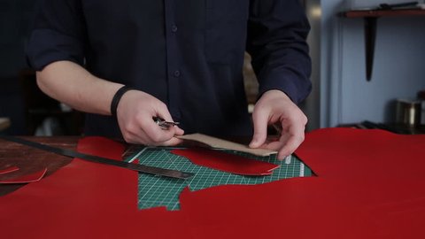 Tanner in a tannery, carves out a special pattern for blanks for the manufacture of the purse