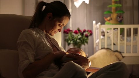 Pig Lactation - Young beautiful mother, breastfeeding her newborn baby boy at night, dim  light. mom breastfeeding infant