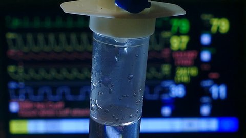 I.V. Intravenous saline drip with Patient Monitor background in the emergency room , Close-up