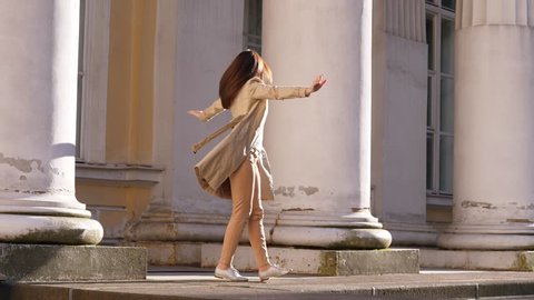 Business woman in elegant trench coat dancing, spinning around and celebrate business success
