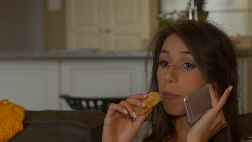 Attractive Woman Eats Cheese Talking On Phone On A Couch
