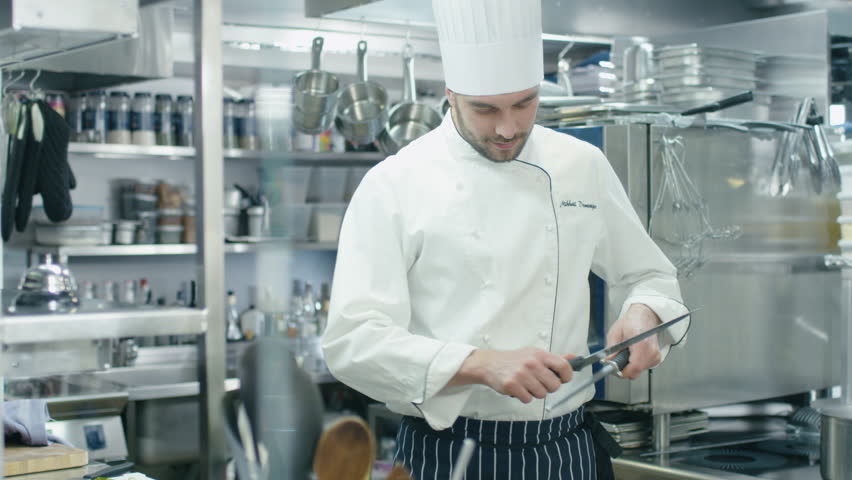 Restaurant Kitchen Video a cook sharpening a knife in a restaurant kitchen stock footage Restaurant Kitchen Video a cook sharpening a knife in a restaurant kitchen stock footage