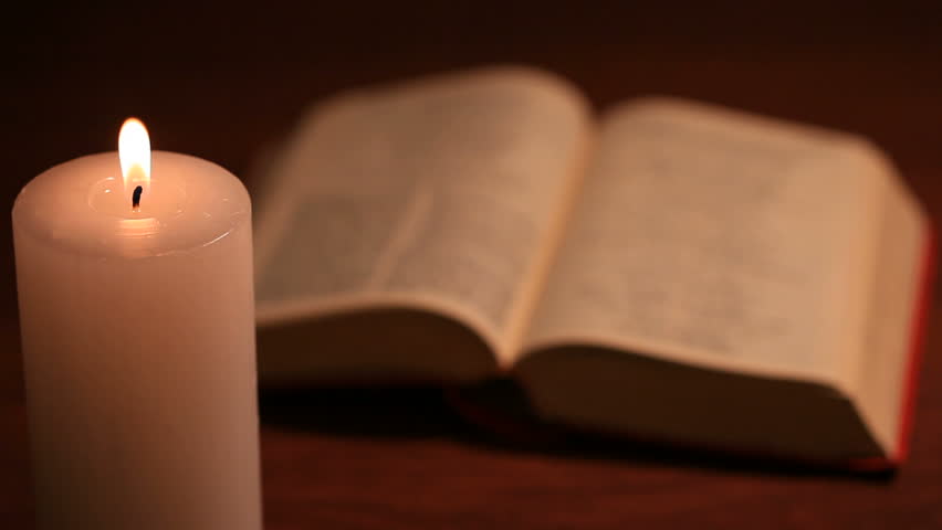 An Open Bible With A Rosary And A Lighted Blurry White Candle On ...