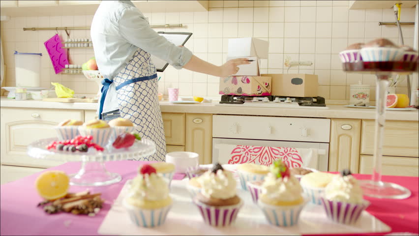 Woman Decorating Cupcakes woman decorating cup-cakes with sprinkling and berries / shot of Woman Decorating Cupcakes woman decorating cup-cakes with sprinkling and berries / shot of