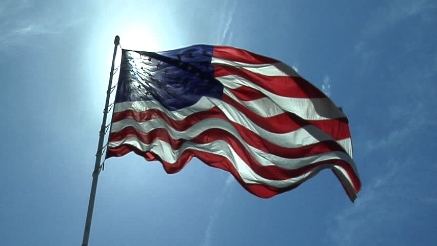 Official United States Of America Flag Flying In The Wind With The Sun