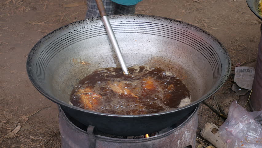 Frying Fish In A Large Outdoor Wok Cooking Over Makeshift Fire Pit