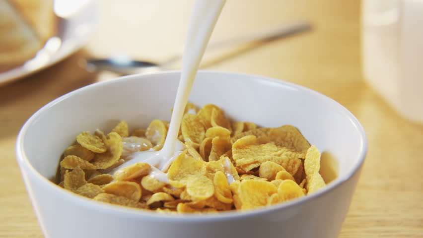 Pouring Corn Flakes And Milk Inti A Breakfast Bowl With Coffee Cup In ...