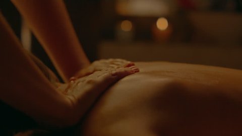 Receiving Body Massage at Spa Club. Hands massaging the back. Camera on dolly. Evening light.