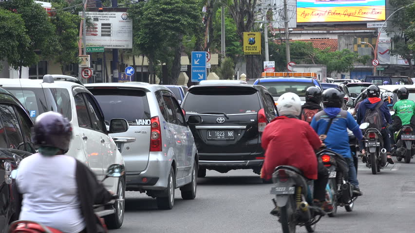 SURABAYA, INDONESIA - APRIL 2017: Motorbikes Ride Past Cars Stuck In ...