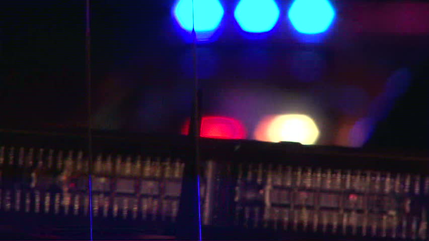 Police lights flashing at night downtown at crime scene, close up.