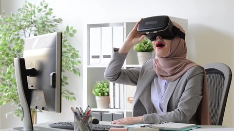 beautiful young lady muslim worker watching 3D video relaxing through virtual reality device.