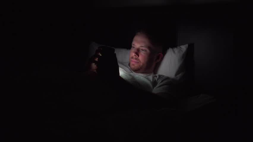 Image result for man looking at cell phone in the dark