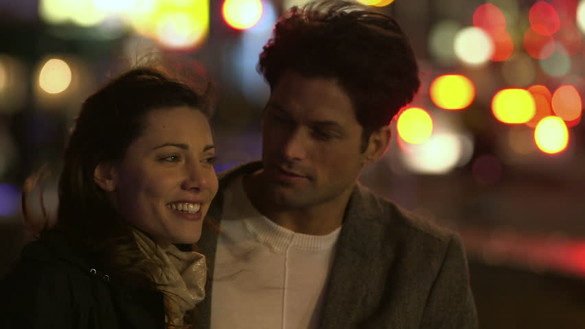 A Cute Young Couple Walk Through A City At Night Together. Medium Shot ...