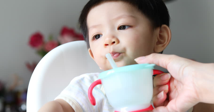 Cute Baby Boy Drinking Water From Straw In Training Cup