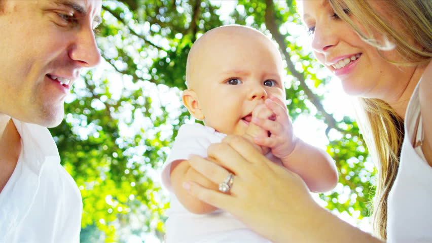 Loving Young Caucasian Parents Holding Up Happy Baby Son In Sunshine ...